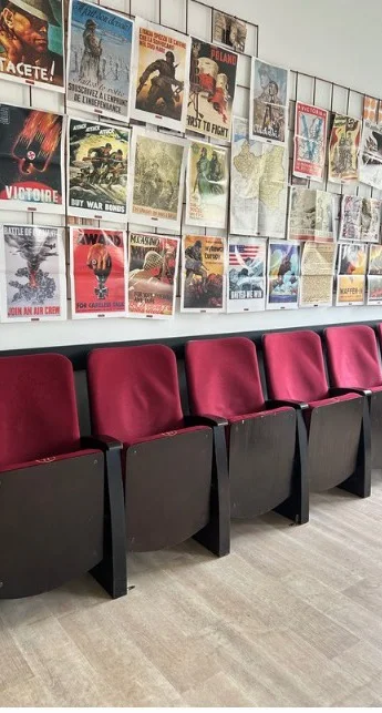 Sala kinowa LO Akademickiego: bordowe fotele i ściana plakatów