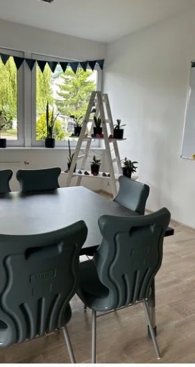 Sala lekcyjna z szarymi krzesłami i stołem